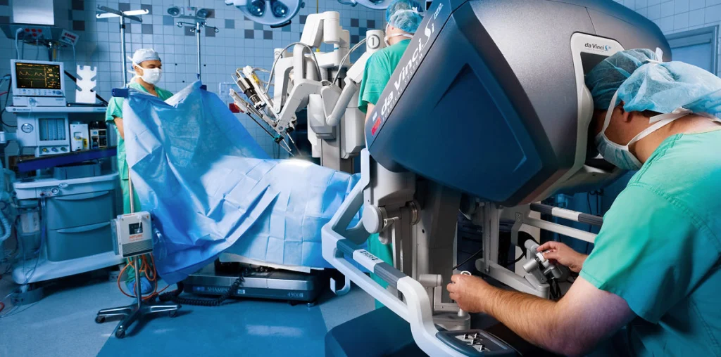 A surgical team operates a robotic surgical system in a sterile operating room, focused on the patient covered with a blue drape.