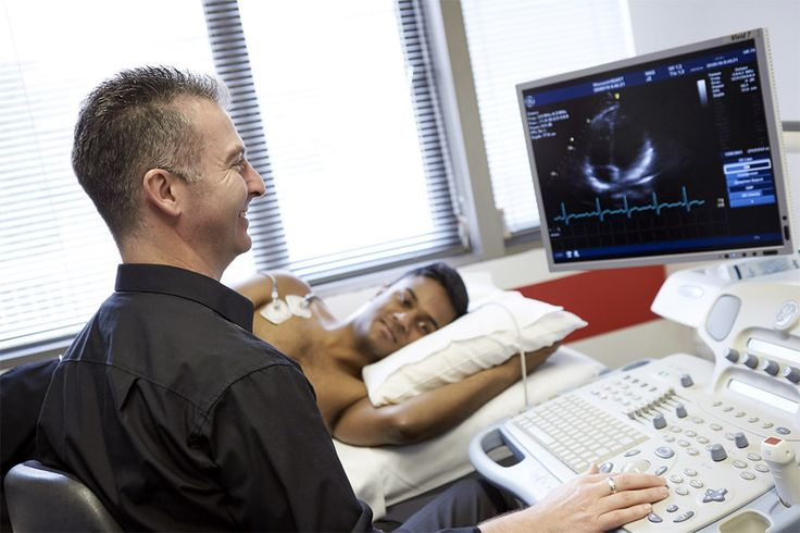A medical professional conducts an ultrasound examination, observing images on the monitor while the patient lies on a medical bed.