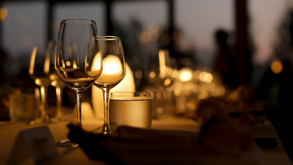 A dimly lit table set with elegant glassware and soft glowing lights, creating a warm and inviting dinner atmosphere.