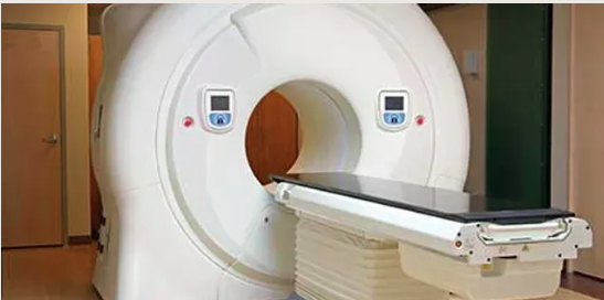 A CT scanner with a wide circular opening and a sliding examination table, set in a modern medical facility.