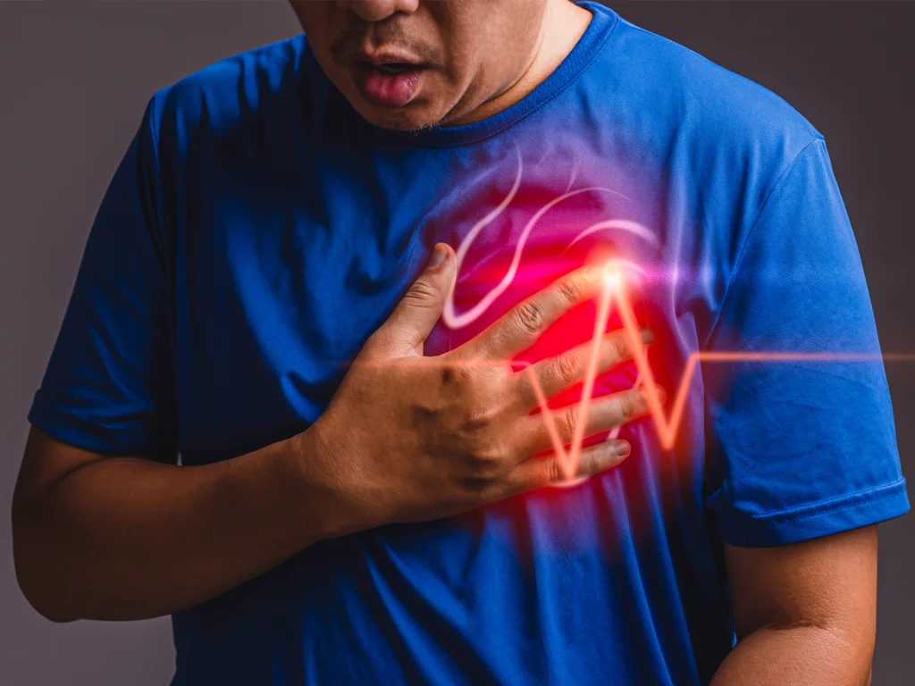 A man in a blue shirt clutches his chest, with a glowing red heartbeat graphic symbolizing heart pain or distress.